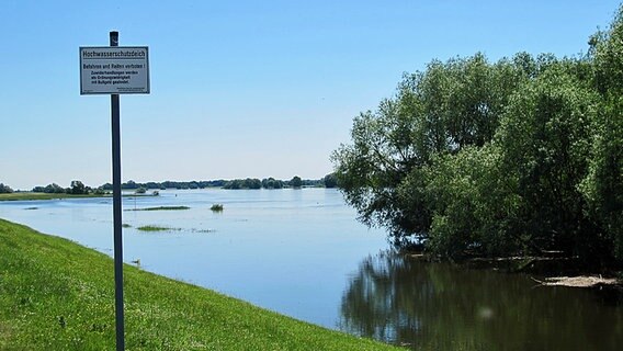Ein Schild mit der Aufschrift "Hochwasserschutzdeich - Befahren und Reiten verboten!" steht vor der Elbe in Dömitz. © NDR Foto: Christian Heiden
