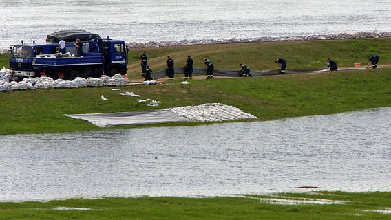 Helfer des THW verbauen in Dömitz auf dem Deich zusätzliche Schutzmaßnahmen gegen das Hochwasser der Elbe. © dpa-Bildfunk Foto: Jens Büttner