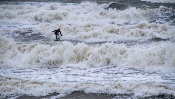 Ein Surfer springt mit seinem Surfbrett über Wellen in der Ostsee vor Binz. © dpa Foto: Stefan Sauer
