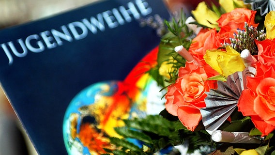 Eine Jugendweihe-Urkunde liegt neben einem Blumenstrauß. © picture-alliance Foto: Andreas Lander