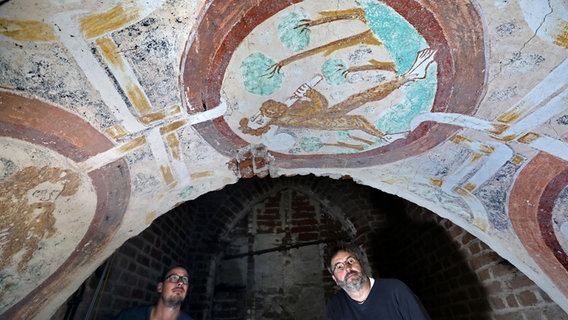 Die Restauratoren Marcus Mannewitz (l-r) und Bastian Hadler schauen auf eine Wandmalerei mit dem Motiv "Wilder Mann", die bei Arbeiten in der Kirche in einem sonst unzugänglichen Raum oberhalb der Orgel entdeckt wurden. Die Restauratoren Marcus Mannewitz (l-r) und Bastian Hadler schauen auf eine Wandmalerei mit dem Motiv "Wilder Mann", die bei Arbeiten in der Kirche in einem sonst unzugänglichen Raum oberhalb der Orgel entdeckt wurden. © dpa-Bildfunk Foto: Bernd Wüstneck