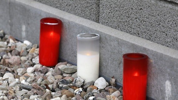 Drei Kerzen stehen vor dem Haus in Rövershagen, in dem ein Mann seine Schwester, seinen Vater und seine Mutter ermordet haben soll. © dpa-Bildfunk Foto: Bernd Wüstneck