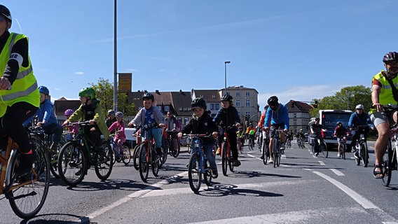 Kinder auf Fahrrädern kommen auf die Kamera zu. Sie fahren auf einer öffentlichen Straße am Wismarer Hafen entlang. © NDR Foto: Christoph Woest