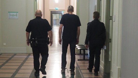 Ein Angeklagter mit Fußfesseln wird von zwei Wachmännern durch den Flur des Landgerichts Schwerin geführt. © Andreas Frost Foto: Andreas Frost