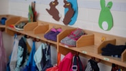 Garderobe mit Schuhen, Jacken und gebastelten Osterhasen in einem Kindergarten © IMAGO / Sven Simon Foto: IMAGO / Sven Simon