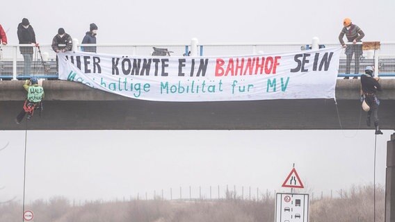 Demonstranten hängen am Geländer einer Brücke über die A20 ein Transparent auf. © dpa Foto: Frank Hormann