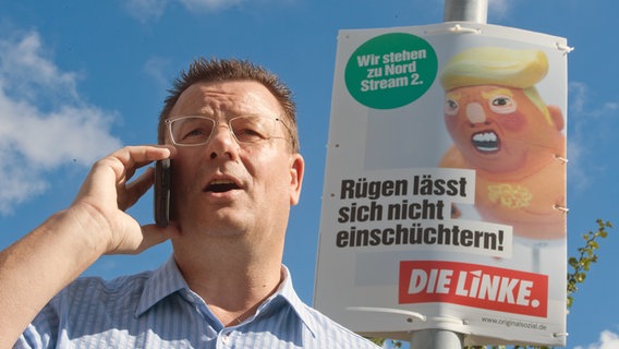 Frank Kracht (parteilos, Kandidat der Linken) Bürgermeister von Sassnitz steht im Jahr 2020 im Stadtgebiet von Sassnitz vor einem Wahlplakat mit dem Schriftzug "Wir stehen zu Nord Stream 2". © picture alliance/dpa | Stefan Sauer Foto: picture alliance/dpa | Stefan Sauer