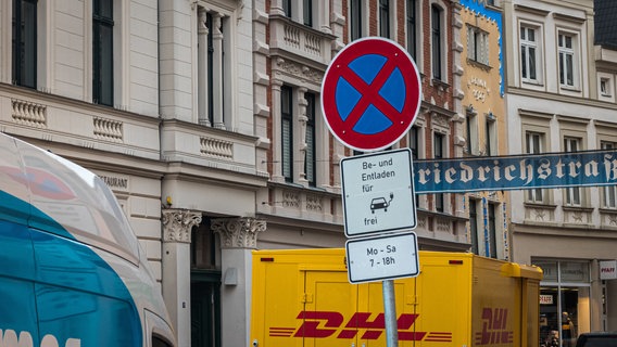 Ein Verkehrsschild, zusammengesetzt aus einem absoluten Halteverbotsschild, darunter zwei weiße Schilder mit ergänzenden Informationen ("Be- und Entladen für Elektrofahrzeuge frei" und "Mo-Sa 7 - 18 Uhr"). © NDR Foto: Christoph Loose