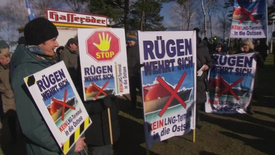 Demostranten stehen mit Schildern in Baabe auf Rügen, um gegen ein geplantes LNG-Terminal zu protestieren. © NDR Foto: Screenshot