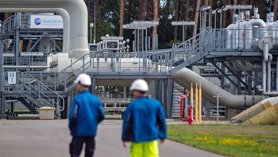 Rohrsysteme und Absperrvorrichtungen in der Gasempfangsstation der Ostseepipeline Nord Stream 1 und der Übernahmestation der Ferngasleitung OPAL. Im Vordergrund sind unscharf zwei Arbeiter mit Helmen zu sehen. © dpa Foto: Stefan Sauer