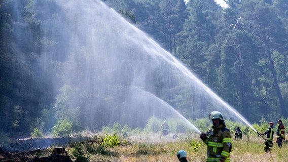 Feuerwehrleute wässern die Brandschutzschneisen bei der Bekämpfung eines Feuers auf einem ehemaligen Truppenübungsplatz bei Lübtheen. © dpa Foto: Jens Büttner