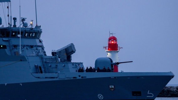Ein Militärschiff der Bundesmarine fährt am Leuchtfeuer auf der Ostmole von Warnemünde vorbei Richtung Marinestützpunkt Hohe Düne. © picture alliance/dpa Foto: Jens Büttner