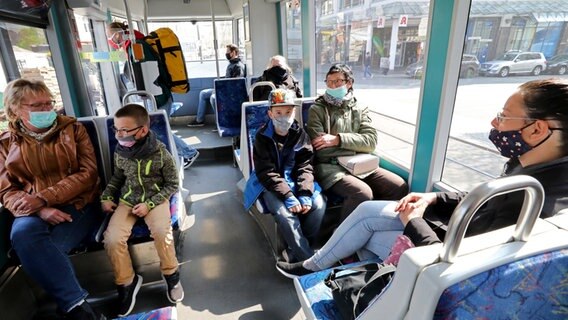 Rostock: Fahrgäste sitzen mit Mund-Nasenbedeckungen in einer Straßenbahn. © dpa-Bildfunk Foto: Bernd Wüstneck