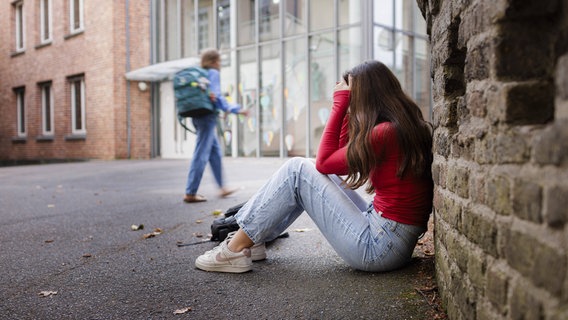 Ein Mädchen sitzt auf dem Boden eines Schulhofes. © Ute Grabowski/imago/phototek Foto: Ute Grabowski/imago/phototek