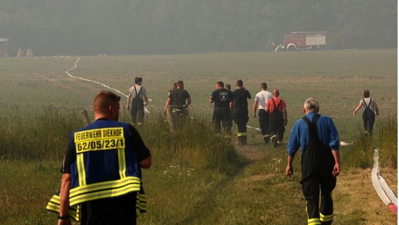 Feuerwehrleute laufen zu einem brennenden Wald- und Torfmoorgebiet. Wegen des unwegsamen Geländes mussten Schläuche hunderte Meter weit verlegt werden. © dpa Foto: Bernd Wüstneck