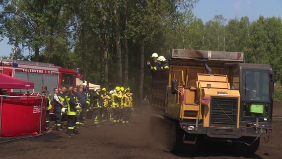 Feuerwehrleute werden mit einem Kettenfahrzeug der ansässigen Torfabbaufirma zu ihrem Einsatz am brennenden Wald- und Torfmoorgebiet bei Göldenitz gebracht. Das unwegsame Gelände erschwert die Löscharbeiten. © NDR Foto: NDR