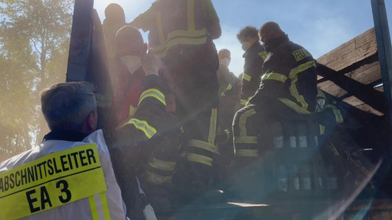 Ein Einsatzteam der Feuerwehr trifft letzte Absprachen von der Ladefläche eines Kettenfahrzeugs aus. Die ansässige Torfabbaufirma hat die Fahrzeuge für die Löscharbeiten am brennenden Wald- und Torfmoorgebiet bei Göldenitz zur Verfügung gestellt. © NDR Foto: NDR