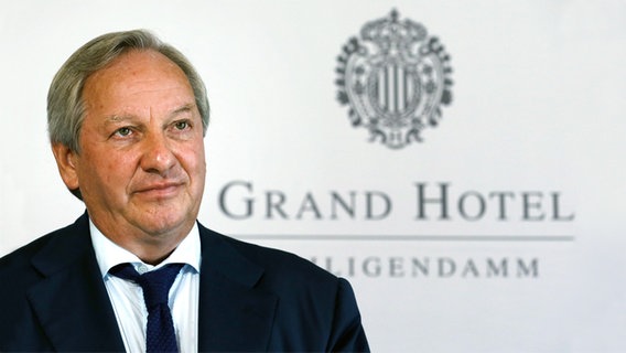 Der hannoversche Wirtschaftsprüfer Paul Morzynski steht vor dem Logo des Grand Hotels Heiligendamm. © dpa - Bildfunk Foto: Bernd Wüstneck