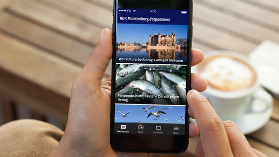 Blick auf ein schwarzes Smartphone, dass die neue NDR Mecklenburg-Vorpommern App zeigt © NDR 