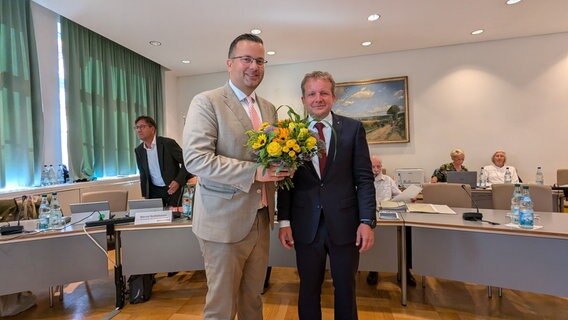 Sebastian Ehlers (links) mit Blumenstrauß. Rechts daneben Oberbürgermeister Rico Badenschier. © NDR Foto: Christoph Loose