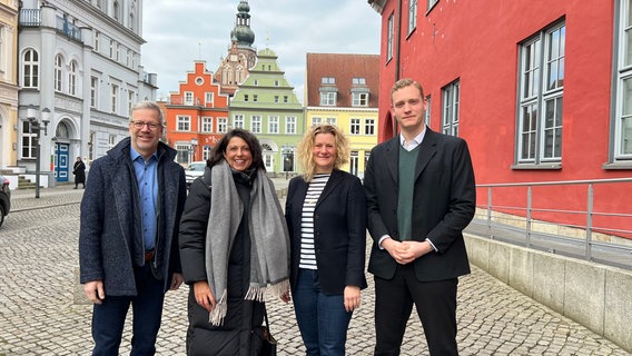 Stefan Fassbinder (Greifswalder Oberbürgermeister), Madeleine Tolani (Präsidentin der Bürgerschaft Greifswald), Anja Rosswinkel (Kanzlei der Bürgerschaft) und Jonas Dietrich (Leiter der Kanzlei der Bürgerschaft) stehen nebeneinander. Im Hintergrund sind die Greifswalder Innenstadt und der Dom zu sehen. Stefan Fassbinder (Greifswalder Oberbürgermeister), Madeleine Tolani (Präsidentin der Bürgerschaft Greifswald), Anja Rosswinkel (Kanzlei der Bürgerschaft) und Jonas Dietrich (Leiter der Kanzlei der Bürgerschaft) stehen nebeneinander. Im Hintergrund sind die Greifswalder Innenstadt und der Dom zu sehen. © keine Foto: Hannah Freitag