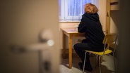 Eine Frau blickt in einem Frauenhaus aus dem Fenster. © Sophia Kembowski 