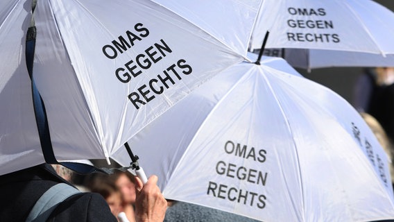 Weiße Regenschirme mit dem Aufdruck "Omas gegen Rechts" werden bei einer Demonstration aufgespannt. (Themenbild) © dpa- Foto: Karl-Josef Hildenbrand/dpa