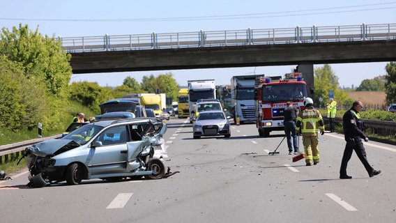 Ein beschädigtes Auto steht quer auf der Autobahn. Andere Fahrzeuge stehen im Hintergrund. Einsatzkräfte von Feuerwehr und Polizei stehen auf der Straße. © Stefan Tretropp Foto: Stefan Tretropp