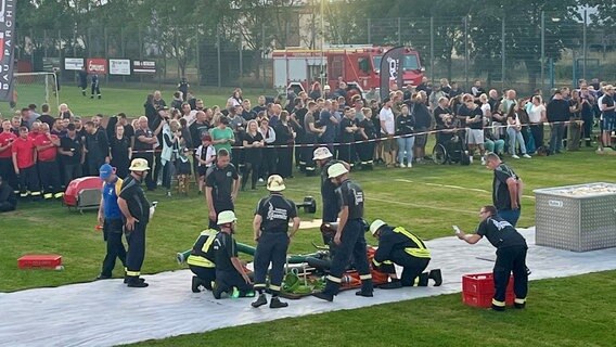 Feuerwehrleute auf einem Sportplatz beim Wettkampf. Löschgeräte sind zu sehen. Im Hintergrund Zuschauer © Feuerwehr Ludwigslust-Parchim 