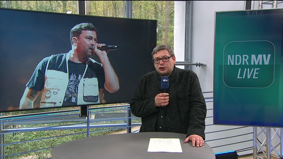 NDR MV Live Moderator Frank Breuner mit dem Rapper Marteria im Hintergrund. © NDR Screenshots Foto: NDR Screenshots