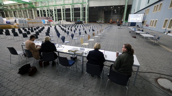 In einer Schiffbauhalle der MV Werft wurde ein Gerichtssaal des Amtsgerichts für die erste Gläubigerversammlung eingerichtet, Mitarbeiter des Insolvenzverwalters warten auf die Gläubiger. © Bernd Wüstneck/dpa Foto: Bernd Wüstneck/dpa