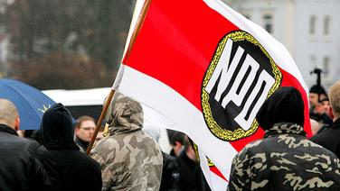 Demonstranten schwenken eine NPD-Fahne. © picture-alliance/CHROMORANGE Foto: Christian Schwier