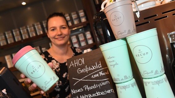 Greifswald: Anne Fischer zeigt in einem Café einen RECUP-Kaffee-Pfandbecher. © dpa-Bildfunk Foto: Stefan Sauer