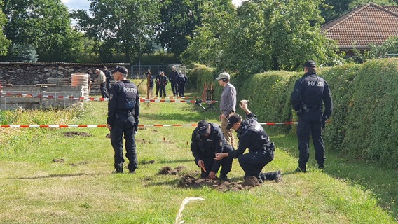 Mehrere Polizisten durchsuchen ein Grundstück mit Hilfe von Metalldetektoren Mehrere Polizisten durchsuchen ein Grundstück mit Hilfe von Metalldetektoren © NDR Foto: Fabian Weißhaupt