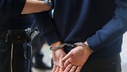 Symbolbild: Ein Polizist führt eine Person in Handschellen ab. © dpa Foto: Christoph Reichwein