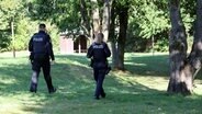 Pragsdorf: Zwei Polizisten sind am See in Pragsdorf unterwegs, wo in unmittelbarer Nähe der Sechsjährige am 14.09.2023 mit schwersten Stichverletzungen gefunden wurde, an denen er später verstarb. © dpa Bildfunk Foto: Bernd Wüstneck