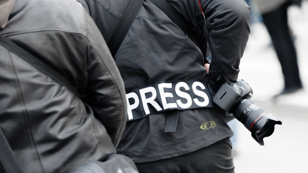 Ein Fotoreporter trägt auf einer Demonstration einen Aufnäher mit dem Text 