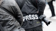 Ein Fotoreporter trägt auf einer Demonstration einen Aufnäher mit dem Text "PRESS" auf seiner Jacke, um sich gegenüber Polizei und Demonstranten als Journalist zu kennzeichnen. © dpa Foto: Markus Scholz