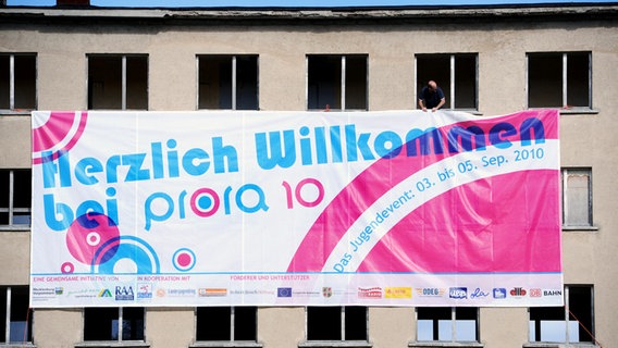 Eine Werbeplakat für die "Prora 10" wird an einer Gebäudewand befestigt.  Foto: Sammlung Sauer / Ursula Düren