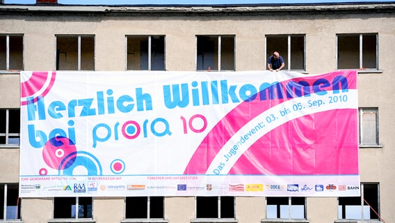 Eine Werbeplakat für die "Prora 10" wird an einer Gebäudewand befestigt.  Foto: Sammlung Sauer / Ursula Düren