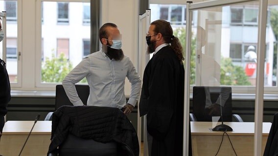 Ein Mann mit Hemd und Jeans unterhält sich mit einem Mann in Anwaltsrobe. Beide haben lange Haare und langen Bart.  Foto: Stefan Tretropp