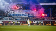 Hansa Rostock-Fans stehen in einer Fan-Kurve und haben Bengalos gezündet - Rauch steigt auf. © NDR 