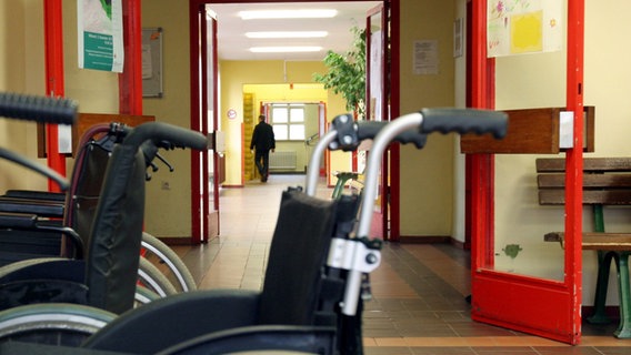 Rollstühle stehen vor einer Tür in einer Werkstatt für behinderte Menschen. © picture alliance/dpa Foto: Felix Frieler