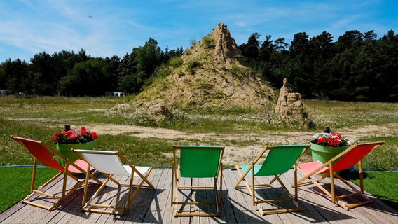 Eine große Sandburg steht auf einer Wiese und davor bunte Liegestühle. © Sandfest Rügen 2018 