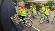 Polizist steht vor Kinder mit Warnwesten und Fahrrädern. © NDR Foto: Chrisoph Loose