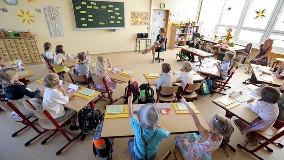 Schüler einer Grundschulklasse sitzen im Halbkreis vor der Tafel. © dpa - Bildfunk Foto: Bernd Wüstneck/dpa