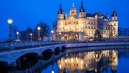 Mecklenburg-Vorpommern, Schwerin: Das Schweriner Schloss spiegelt sich während der so genannten blauen Stunde im Burgsee. © dpa-Bildfunk Foto: Jens Büttner