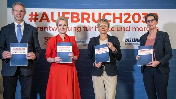 Schwerin: Manuela Schwesig (SPD, 2.v.l.), die Ministerpräsidentin von Mecklenburg-Vorpommern, Simone Oldenburg (2.v.r.), die Fraktionschefin der Linken im Landtag von Mecklenburg-Vorpommern, Thomas Krüger, der Fraktionsvorsitzende der SPD im Landtag von Mecklenburg-Vorpommern, und Wenke Brüdgam (r), die Co-Parteichefin der Linken, stehen mit dem unterzeichneten Koalitionsvertrag zwischen SPD und der Linken für eine gemeinsame Regierungsbildung in Mecklenburg-Vorpommern vor einem Aufstellen mit dem Schriftzug "Aufbruch 2030". © dpa-Bildfunk Foto: Jens Büttner
