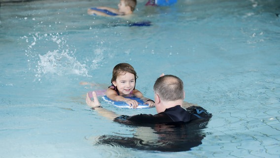 Ein Kind schwimmt auf einen Mann zu. © imago images Foto: biky
