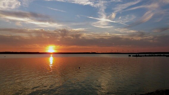 Die am Horizont untergehende Sonne färbt den Himmel und den See orange. © NDR Foto: Andreas Göllner aus Parchim